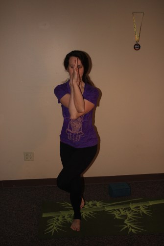 Eagle Pose: wrap the right arm over the left and see if you can bring the palms together. Then, bend the knees and wrap the left leg over the right. 